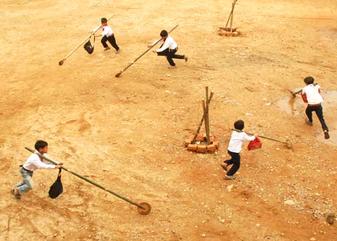 Học sinh vùng cao Sơn Long đẩy "Gậy Trường Sơn" theo vòng tròn trước sân trường trong giờ ra chơi .