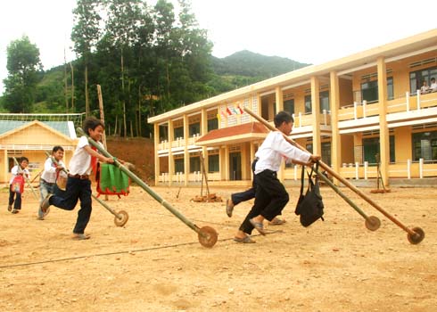 Học sinh trường Tiểu học Sơn Long nằm bên đường Trường Sơn Đông hớn hở đẩy "xe tự chế" vào lớp học.